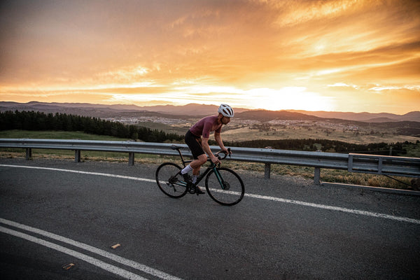 Cyclist climbing a mountain road at sunset near Canberra