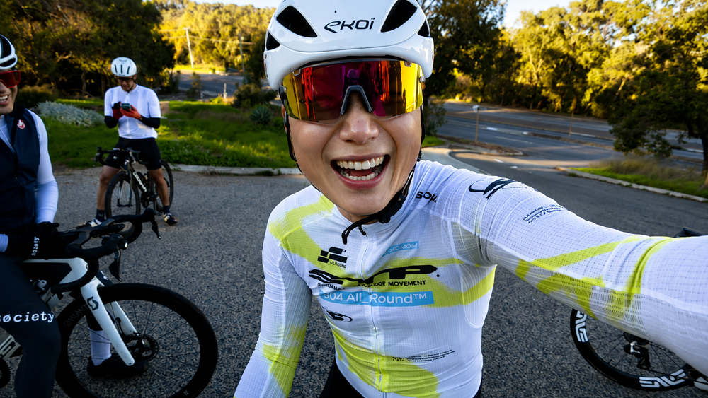 Nat Tan riding on a Perth street, wearing the SOOMOM All-Round OFF STP LS Jersey in Hyperlime, morning sun overhead